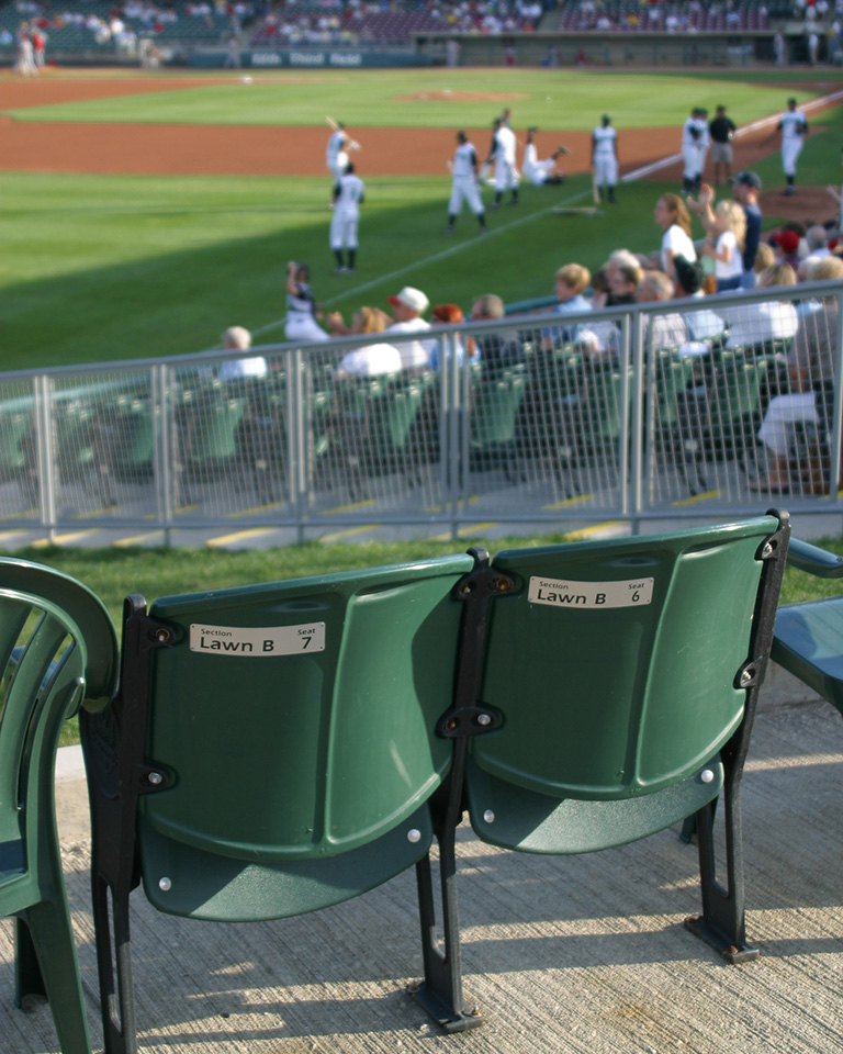 The back of two bleacher seats overlooking a AAA baseball stadium.