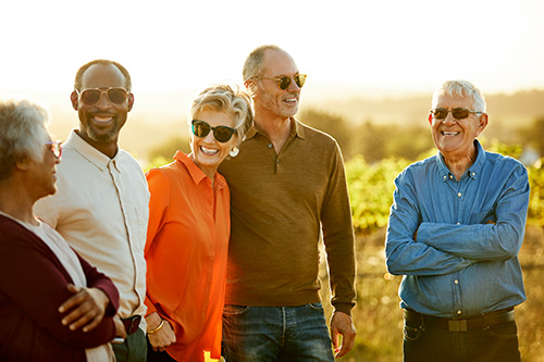 Group Travel Offer Five friends stand in a field during golden hour
