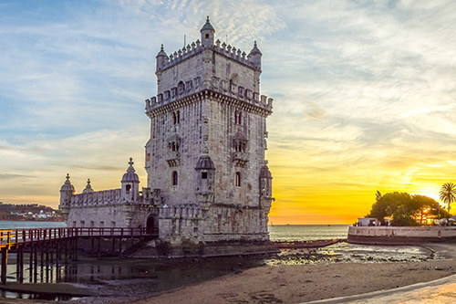 a stone castle at the edge of a beachy shore